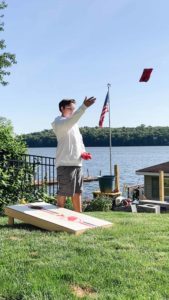 friendly game of Cornhole in a lush summer backyard, epitomizing joyful family bonding over outdoor games.